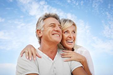 man and woman smiling with blue sky above them