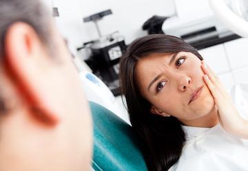 woman holding face from pain during a dental emergency