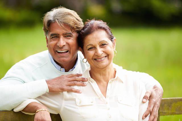 older man and woman smiling while sitting outside